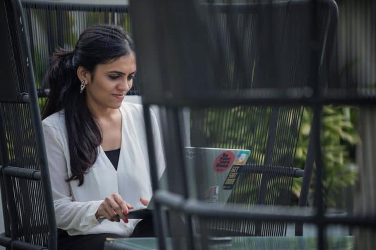 corporate woman sitting in a black modern chair working on her laptop