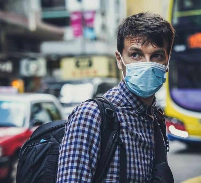 man waiting for bus wearing a COVID-19 face mask