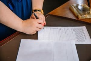 woman signing a contract on a wooden text
