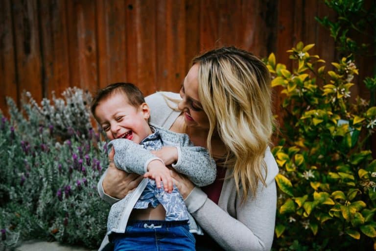 mother playing with her son cheerfully with garden background