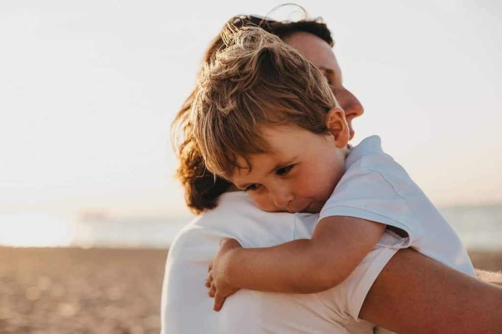 close up of mother hugging her son on the beach