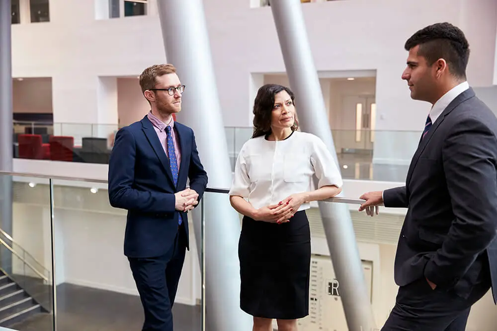 three professionals standing in an office loby having a chat