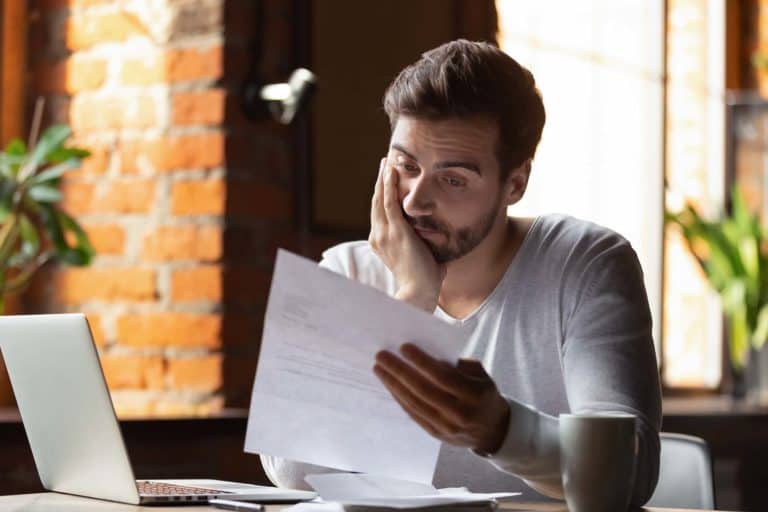 A man looking at a piece of paper while sitting at a desk.