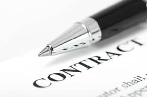 A pen is resting on a contract, symbolizing the determination of worker status as an employee or independent contractor.