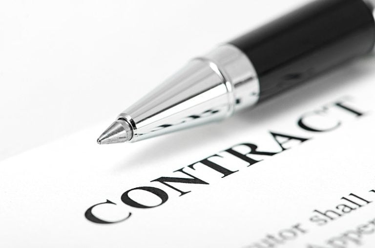 A pen is resting on a contract, symbolizing the determination of worker status as an employee or independent contractor.