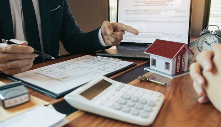 A Conveyancing Paralegal is pointing to a house model on a desk.