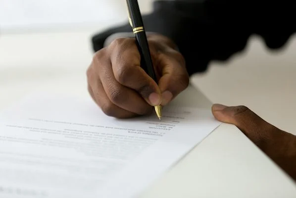 A person exercising their Right of First Refusal by signing a document with a pen.