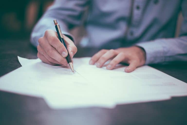 A man exploiting a borrower's disadvantage and signing a document with a pen.