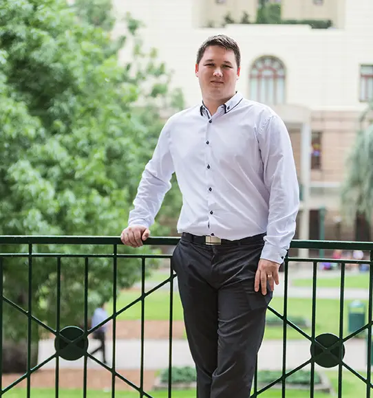 A man standing on a railing in front of a building.