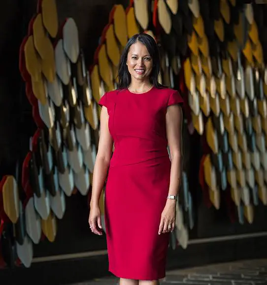 A woman in a red dress standing in front of a wall.