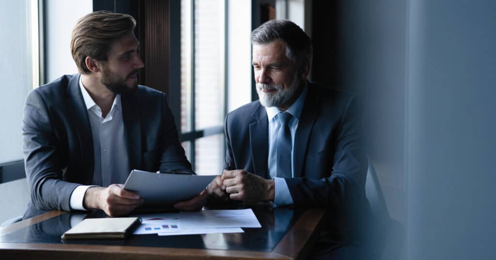 Two businessmen sitting at a table and talking.