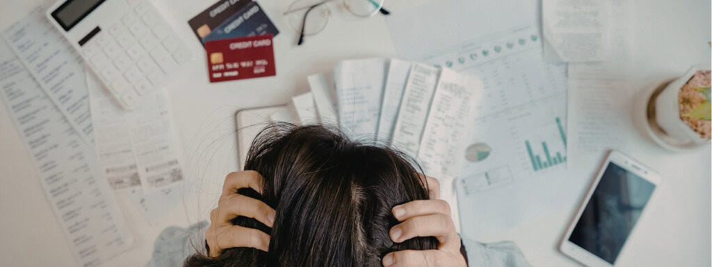 troubled person in front of credit cards, bills and documents