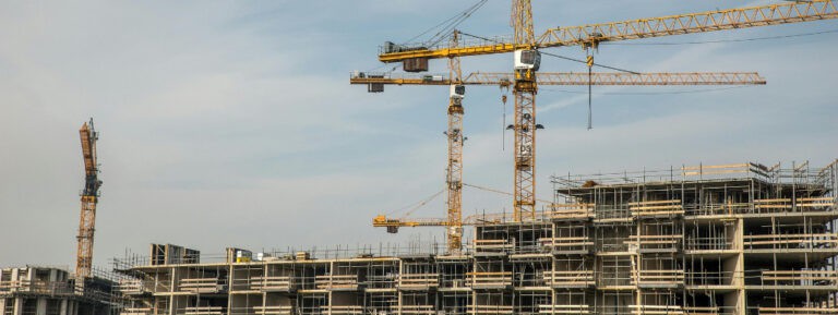 a picture of cranes and ongoing buildings with construction issues with the blue sky as background