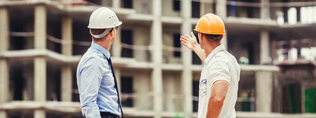 Workers discussing about risks in front of an unfinished building